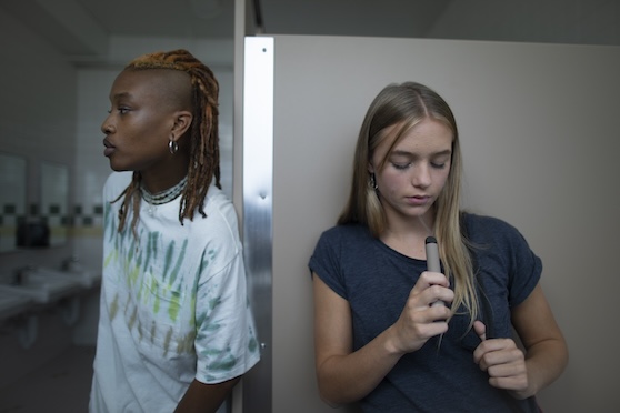 Two students using e-cigarettes in a school bathroom.